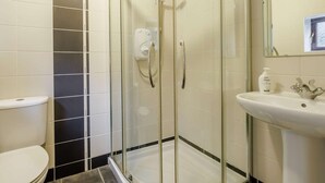 Un bagno con doccia vetrata, lavandino bianco e water.