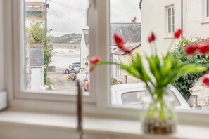 A view through a window with a vase of red flowers in the foreground. - 1 Bed in Bideford (oc-q43354) (Instow)
