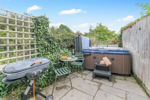 A patio with a grill, a hot tub, and a table with a bottle and oranges. - 1 Bed in Bideford (oc-q43354) (Instow)