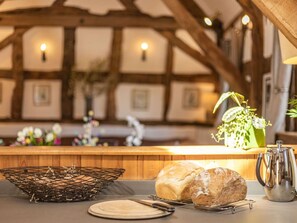 A rustic kitchen with wooden beams, a bread basket, a loaf of bread, a metal pitcher, and a vase with flowers. - 4 Bed in Ludlow (oc-chl22) (Orleton)