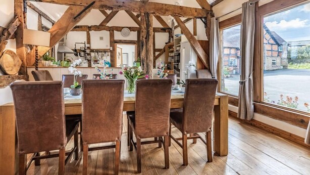 A dining area with wooden beams, a table with chairs, and a view of the outside. - 4 Bed in Ludlow (oc-chl22) (Orleton)