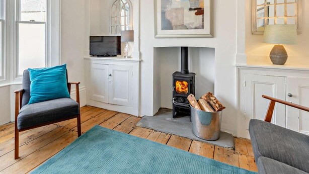 A cozy living room with a fireplace, a television, and a painting on the wall. - 3 Bed in Whitstable (oc-52559) (Whitstable)