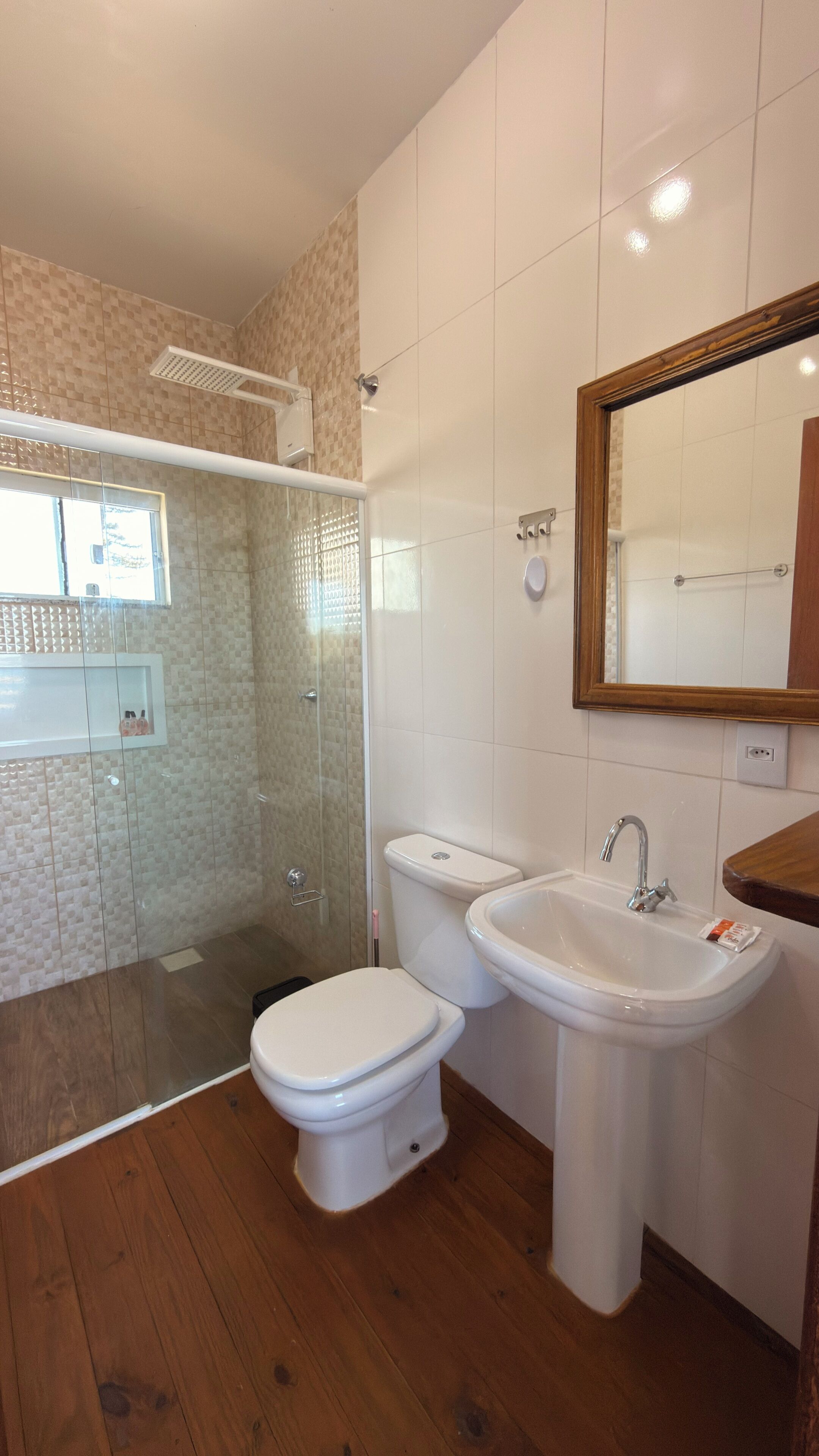 Un baño con ducha, inodoro, lavamanos y espejo.