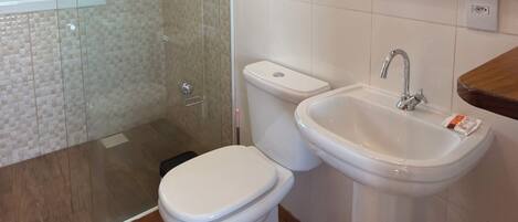 A bathroom with a shower, toilet, sink, and mirror.
