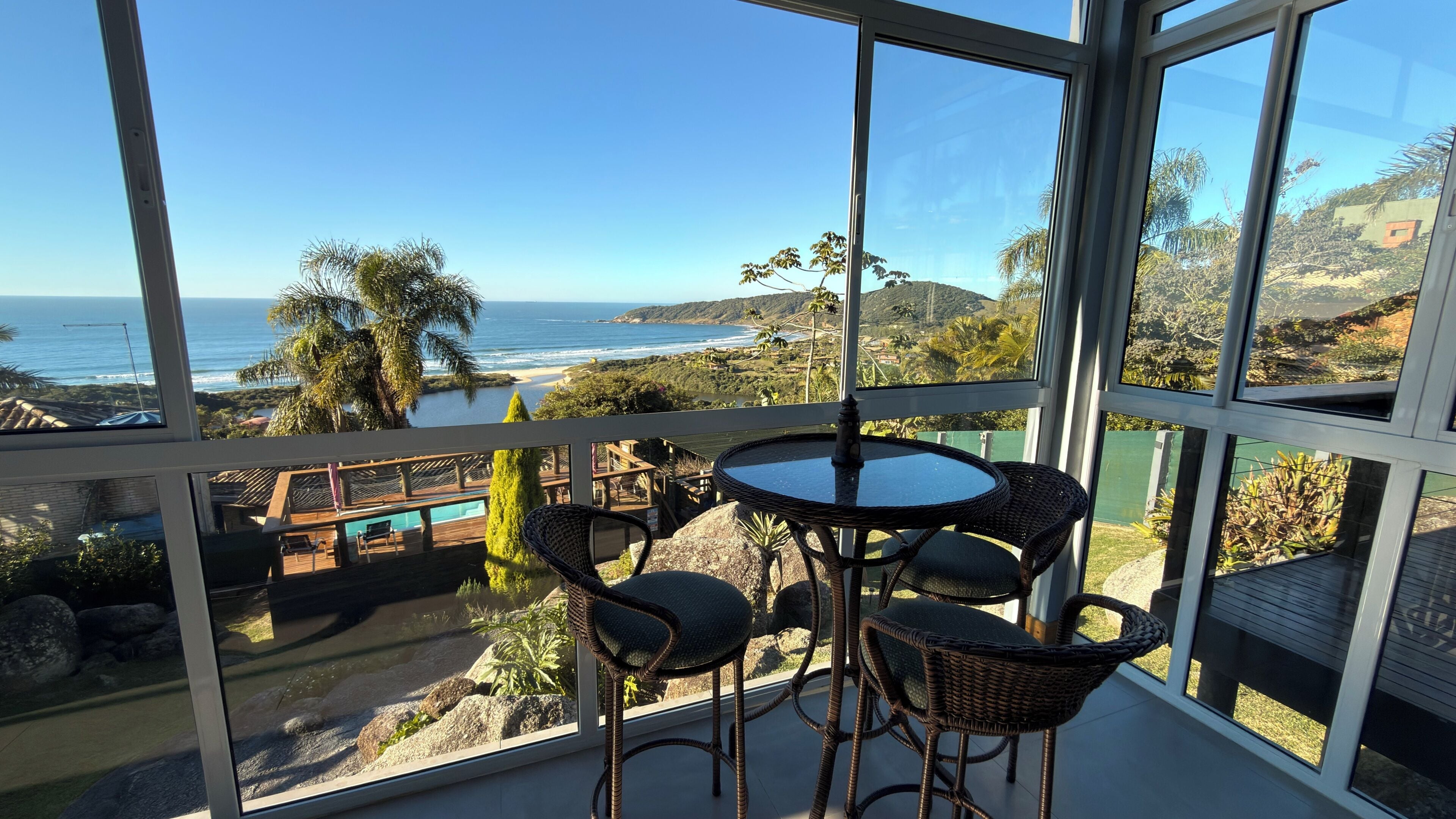 Uma varanda com vista para o oceano, uma mesa redonda e cadeiras de vime.