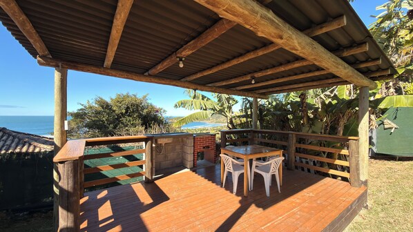 Una terraza de madera con chimenea de ladrillo, una mesa y sillas.