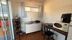 A compact kitchenette with a microwave, coffee maker, and a small sink. - Pousada Farol do Rosa (Imbituba)