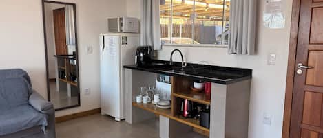 A compact kitchen with a built-in refrigerator, a coffee maker, and a sink.