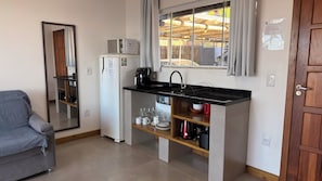 A compact kitchen with a built-in refrigerator, a coffee maker, and a sink. - Pousada Farol do Rosa (Imbituba)