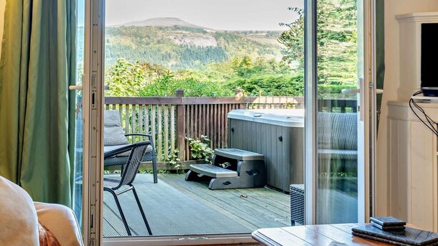 A room with a sliding glass door leading to an outdoor deck with a patio table, a chair, and a barbecue grill. - 1 Bed in Abergavenny (oc-52882) (Gilwern)
