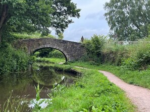 A stone bridge over a calm river, surrounded by lush greenery and a narrow path. - 1 Bed in Abergavenny (oc-52882) (Gilwern)