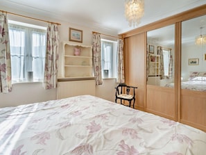 A bedroom with a bed, a chair, a dresser, and a mirror.