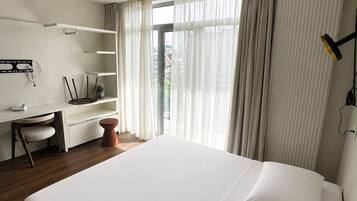 Una habitación de hotel moderna con una cama grande, un escritorio y una silla.