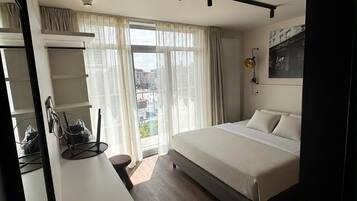 Un dormitorio moderno con cama, escritorio y ventana grande.