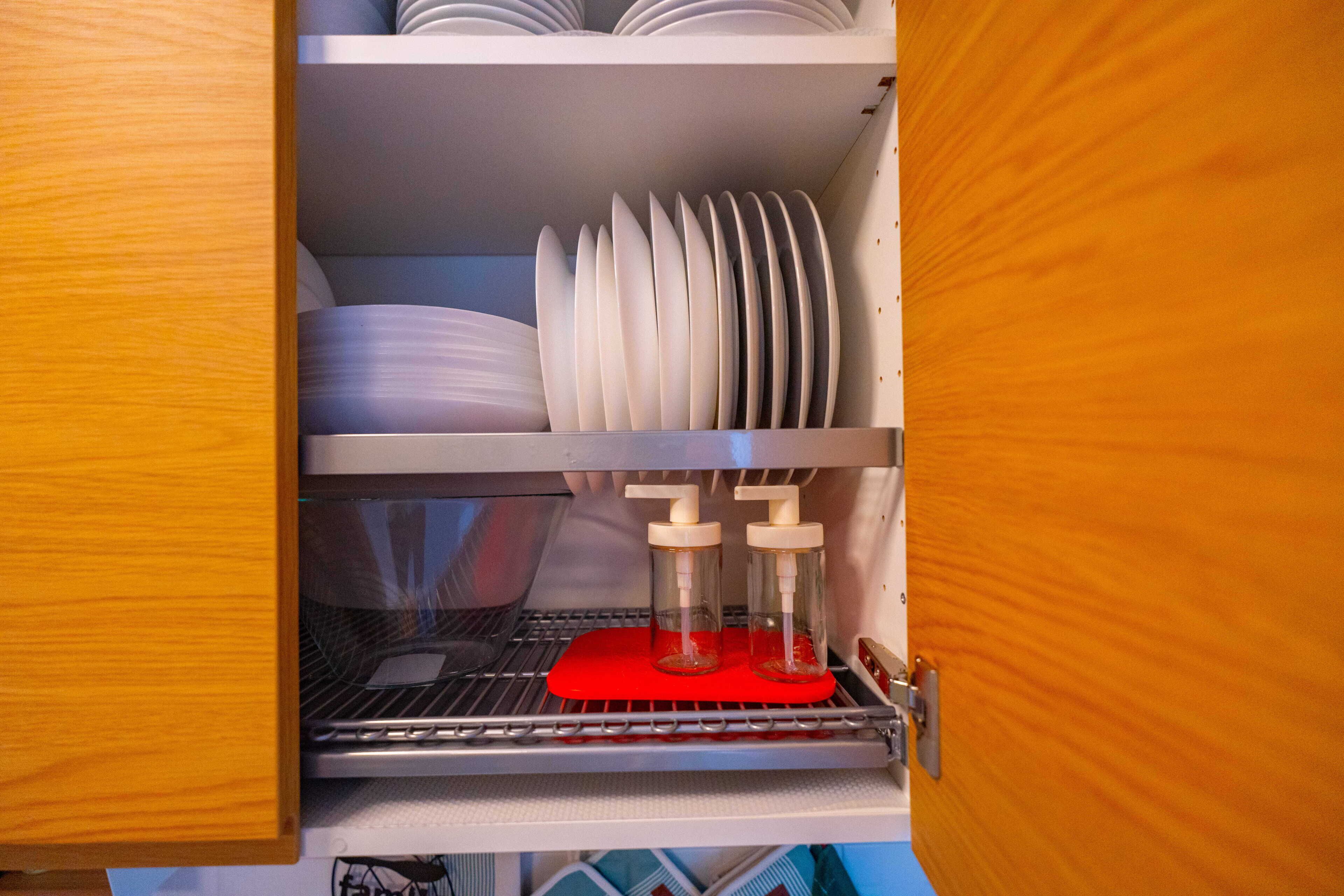 A dishwasher with stacked plates and a red drying rack.