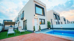 Une maison moderne à deux étages, dotée d’une piscine, d’un espace extérieur aménagé et d’une pelouse bien entretenue.