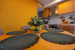A dining area with a round table, black placemats, and a vase with flowers. - Alicante Rent - Villa Costa Luz (Alicante)