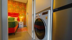 Une chambre d’hôtel avec un lit, un lave-linge et une petite table de chevet.