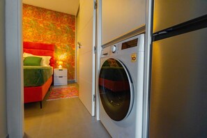 Ein Hotelzimmer mit einem Bett, einer Waschmaschine und einem kleinen Nachttisch.