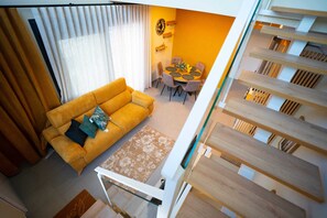 Un salon moderne avec un canapé, une table à manger et des chaises, ainsi qu’un escalier.