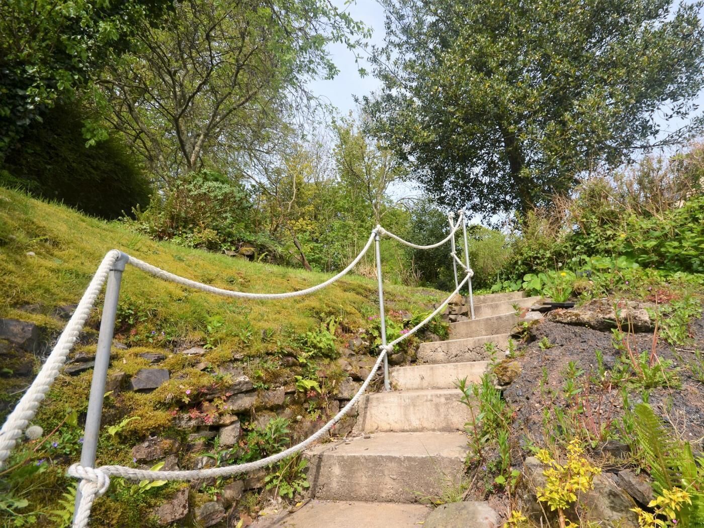 A stone staircase with a rope barrier, surrounded by greenery and trees.