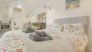 Ein Hotelzimmer mit einem Bett, einem Schreibtisch, einem Sessel, einer Couch, einer Lampe und einem Bild an der Wand.