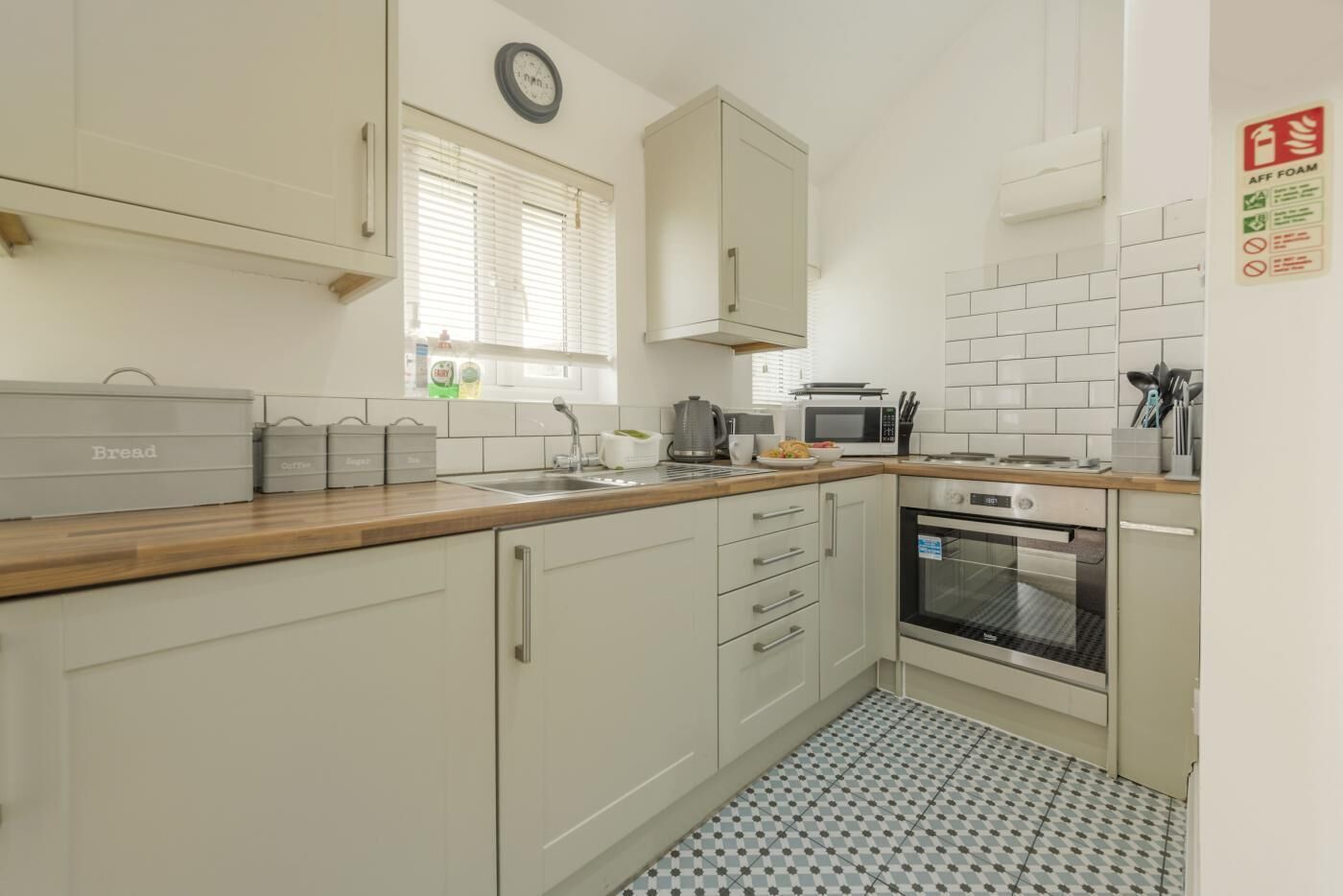 A kitchen with white cabinets, a microwave, an oven, and a sink.