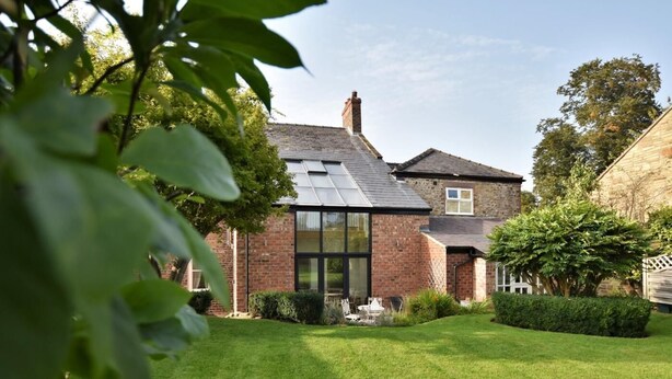 A house with a sloped roof, a brick exterior, and a well-maintained lawn.