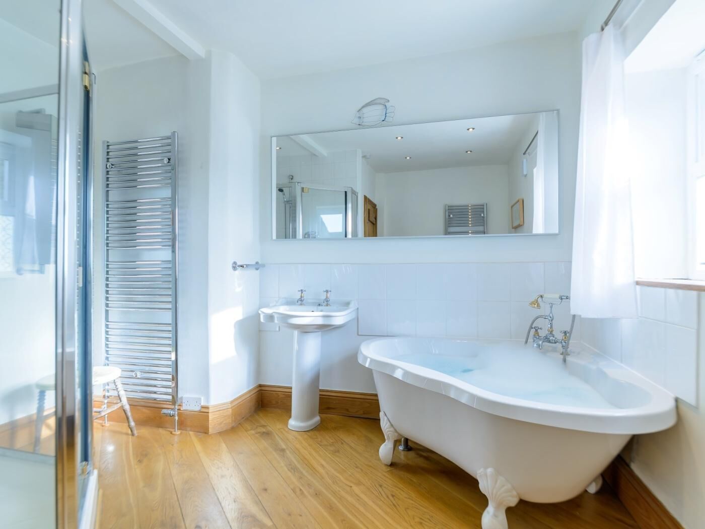 Ein Badezimmer mit einer freistehenden Badewanne, einem Standwaschbecken und einem Spiegel darüber.