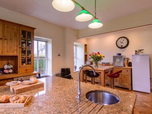 A kitchen with granite countertops, a stainless steel sink, wooden cabinets, a clock, and a window. - 6 Bed in Richmond (oc-52779) (Catterick)