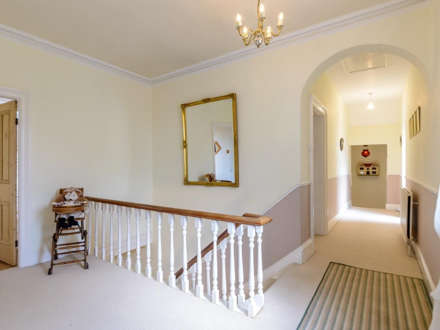 A hallway with a staircase, a chandelier, a mirror, and a radiator.