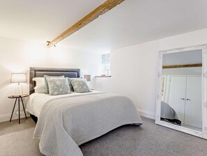 Ein Schlafzimmer mit Bett, Nachttischlampen, einem großen Spiegel und einem Kleiderschrank.