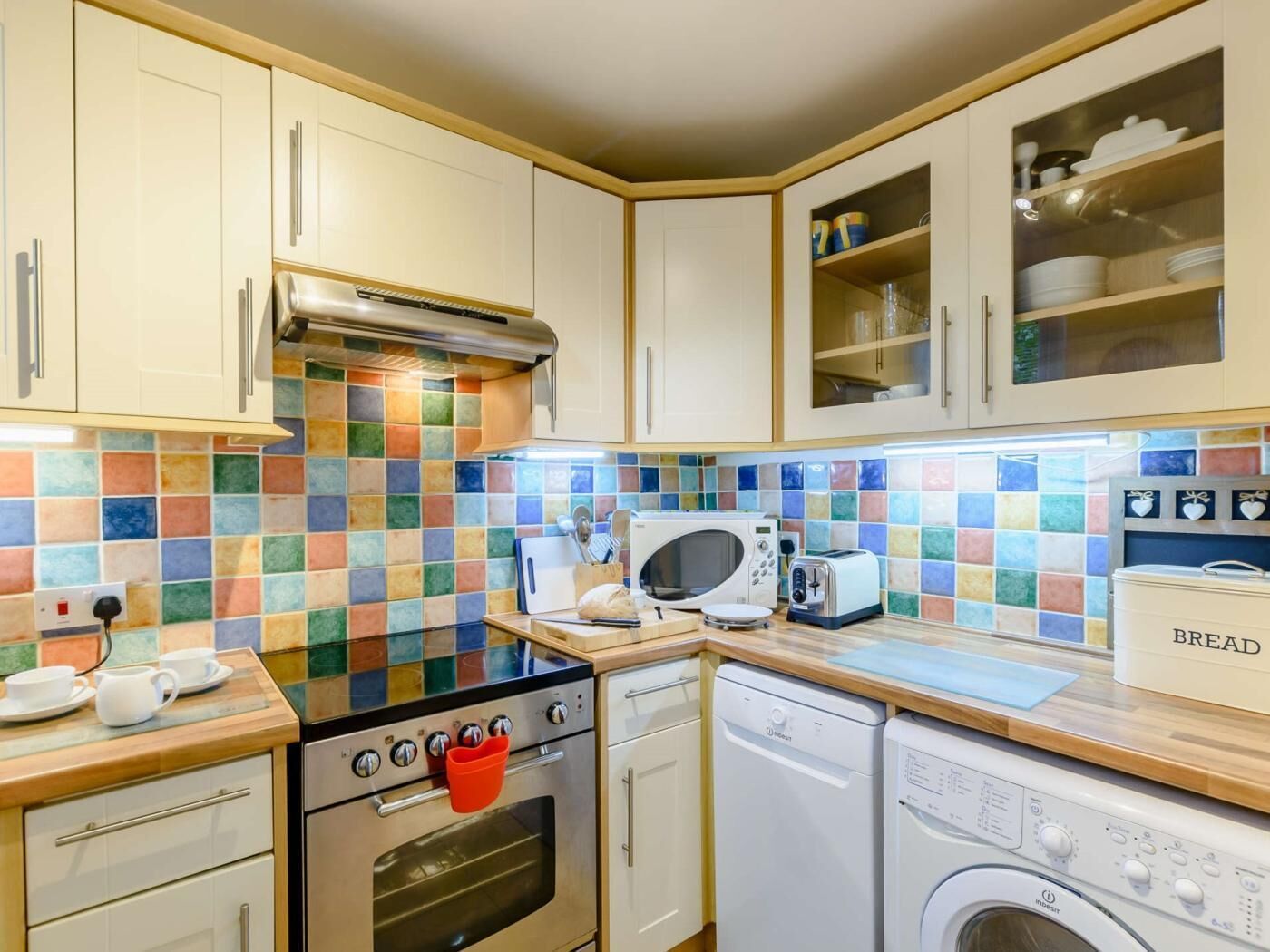 A compact kitchen with a microwave, toaster, oven, and dishwasher.