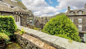 A stone building with a traditional design, a stone wall, and lush greenery. - 1 Bed in Ambleside (oc-53138) (Ambleside)