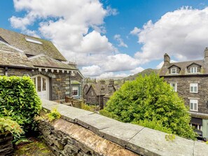 A stone building with a traditional design, a stone wall, and lush greenery. - 1 Bed in Ambleside (oc-53138) (Ambleside)