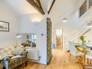 A cozy living room with a plaid sofa, a dining area with a glass table, and a kitchen in the background. - 1 Bed in Ambleside (oc-53138) (Ambleside)