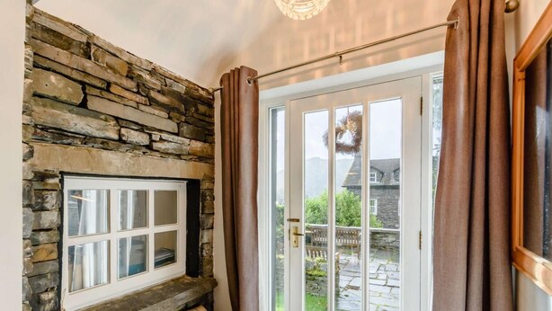 A stone wall, a bench, a door with glass panels, and curtains. - 1 Bed in Ambleside (oc-53138) (Ambleside)