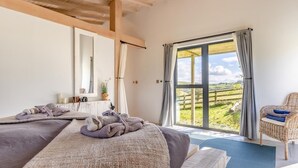 A bedroom with a large window, a bed with towels, a chair, and a mirror. - 1 Bed in Llandrindod Wells (oc-53194) (Llandrindod Wells)