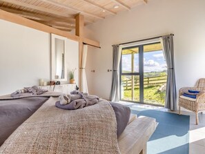 A bedroom with a large window, a bed with towels, a chair, and a mirror. - 1 Bed in Llandrindod Wells (oc-53194) (Llandrindod Wells)