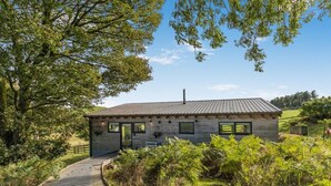 A rustic cabin with a wooden exterior, a metal roof, and a wooden deck leading to the entrance. - 1 Bed in Llandrindod Wells (oc-53194) (Llandrindod Wells)