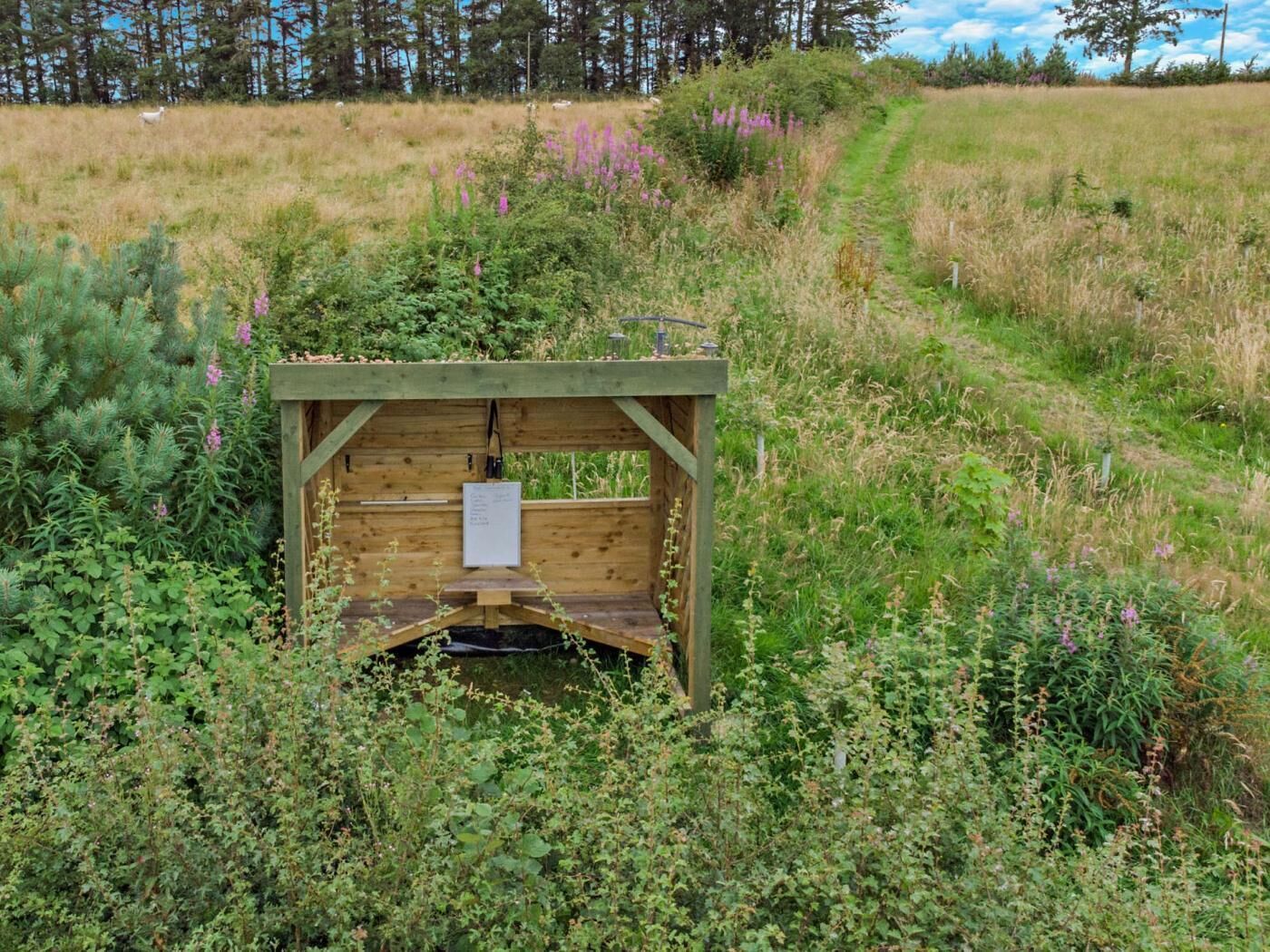 A wooden structure with a bench and a sign in a natural setting.