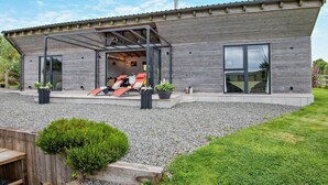 Una casa moderna con un porche cubierto, un ventanal grande y un camino de entrada de grava.