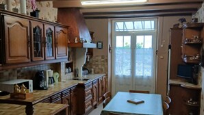 A kitchen with wooden cabinets, a dining table with chairs, and a tiled floor.