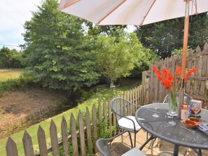 An outdoor patio with a table, chairs, and a wooden fence. - 2 Bed in Sherborne (oc-53673) (Chetnole)