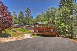 A two-story log cabin with a balcony, surrounded by trees and a clear sky. - Big Bear Ski Chalet - Walk to Slopes & Hot Tub (Big Bear Lake)
