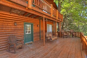 A log cabin with a porch, a green door, and outdoor seating. - Big Bear Ski Chalet - Walk to Slopes & Hot Tub (Big Bear Lake)