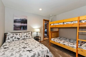 Ein Schlafzimmer mit einem Bett, einem Nachttisch, einer Lampe, einem Etagenbett und einer Tür zu einem anderen Raum.