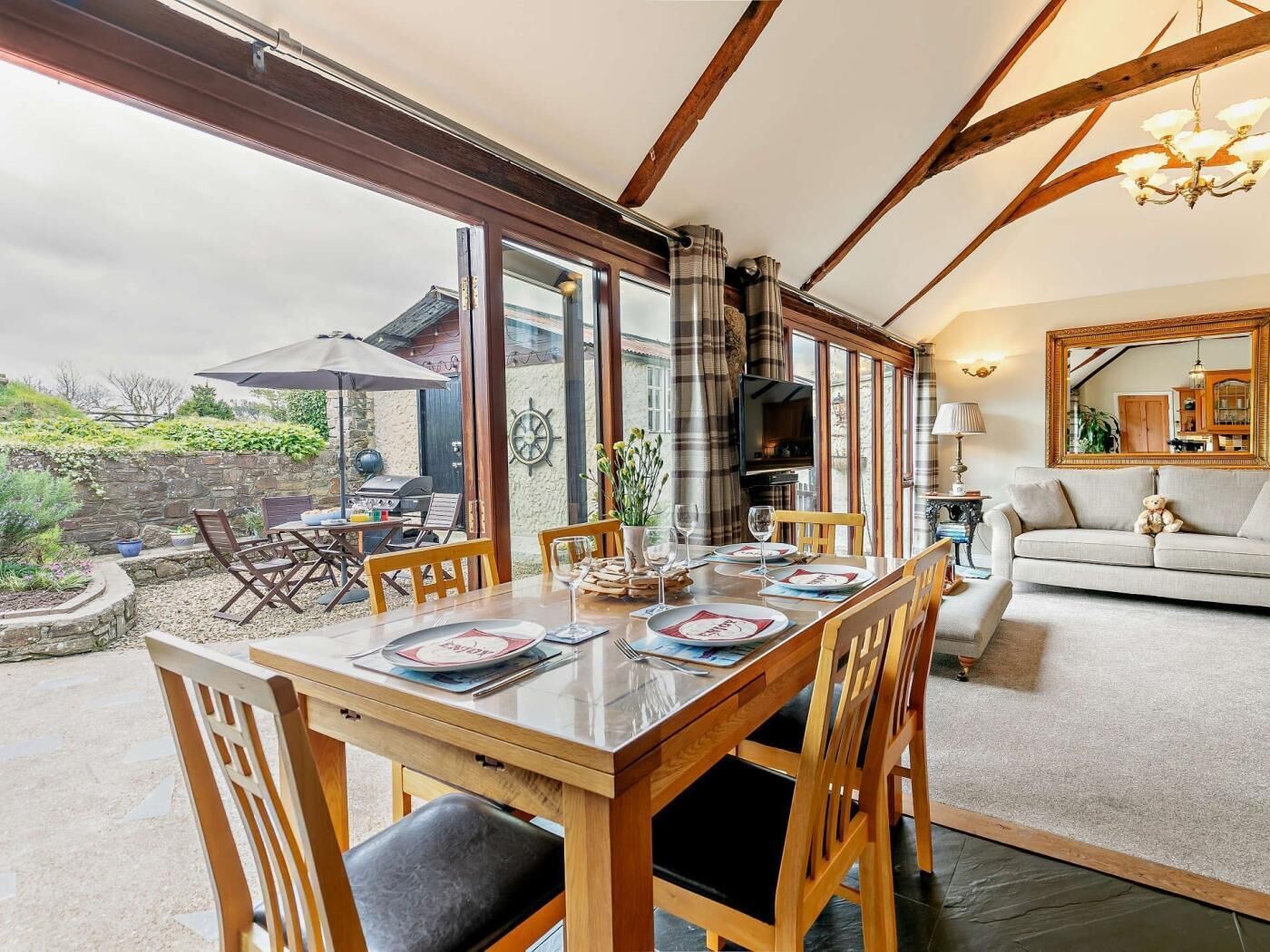 A dining area with a table set for four, a fireplace, and a cozy living room with a sofa and a mirror.