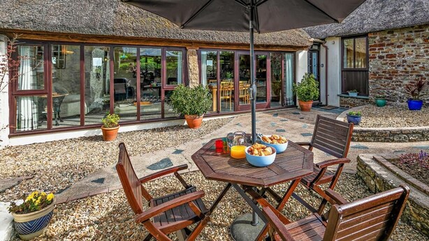 Un patio con una mesa, sillas y una sombrilla grande.