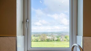 Ein Badezimmer mit Fenster und Blick auf eine ländliche Gegend.